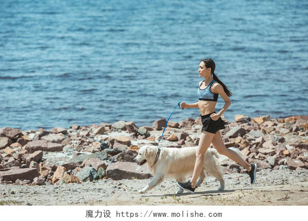 亚洲运动员与狗在海滩上奔跑